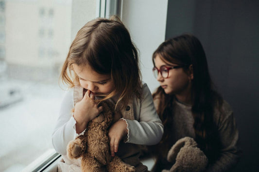 two children looking thoughtfully near a window