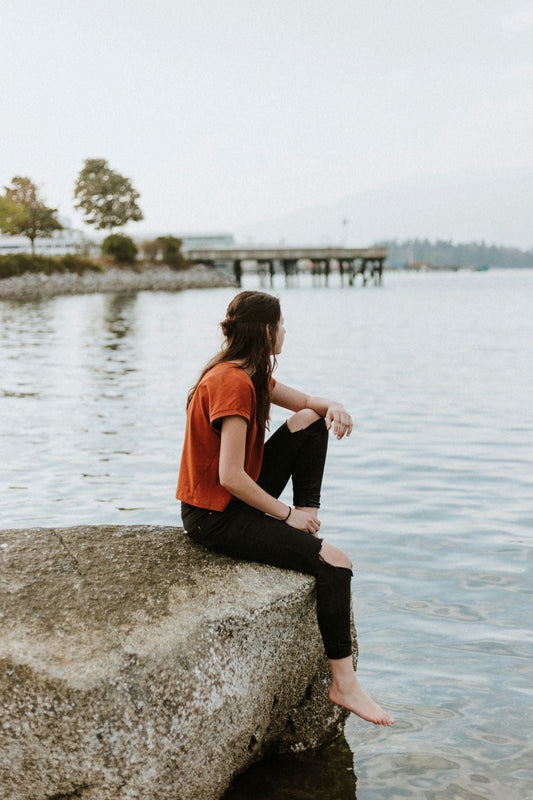 woman sitting on rock looking at the sea