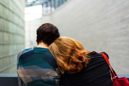 view from behind two women with one resting her head on her friend's shoulder